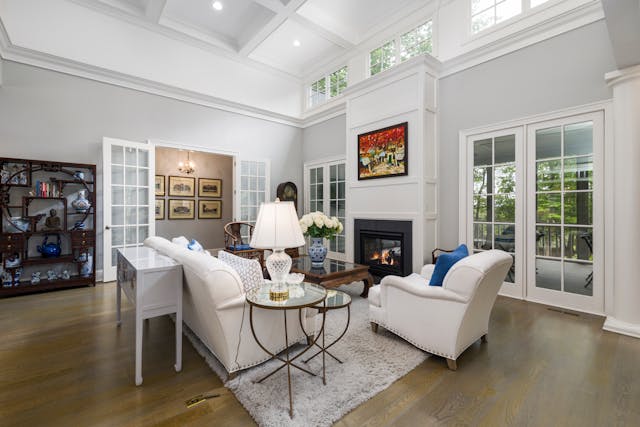 a living room with white walls large windows and wood flooring